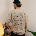 Person wearing a beige t-shirt with 'BIG DOG COFFEE' graphic design, standing in a room with a lamp and plant.